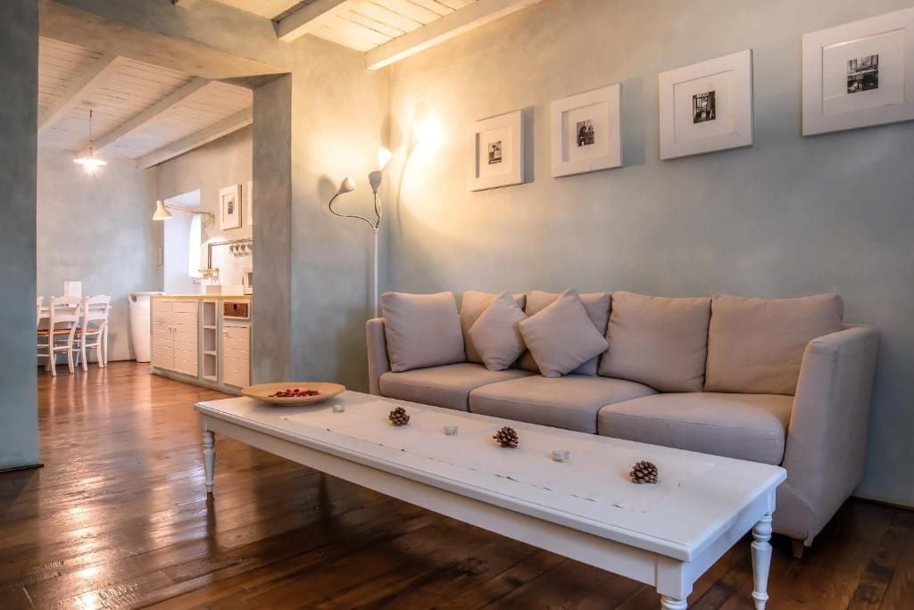 Un salon moderne avec un canapé blanc, une table basse en bois et des tableaux encadrés accrochés au mur.