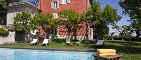 A swimming pool with lounge chairs and a wooden deck.