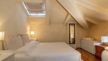 A bedroom with a skylight, a bed, bedside tables, and a small desk.