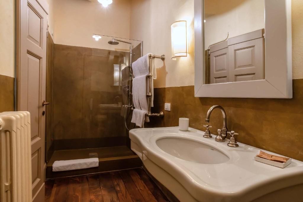 Een badkamer met een douche, wastafel en spiegel.