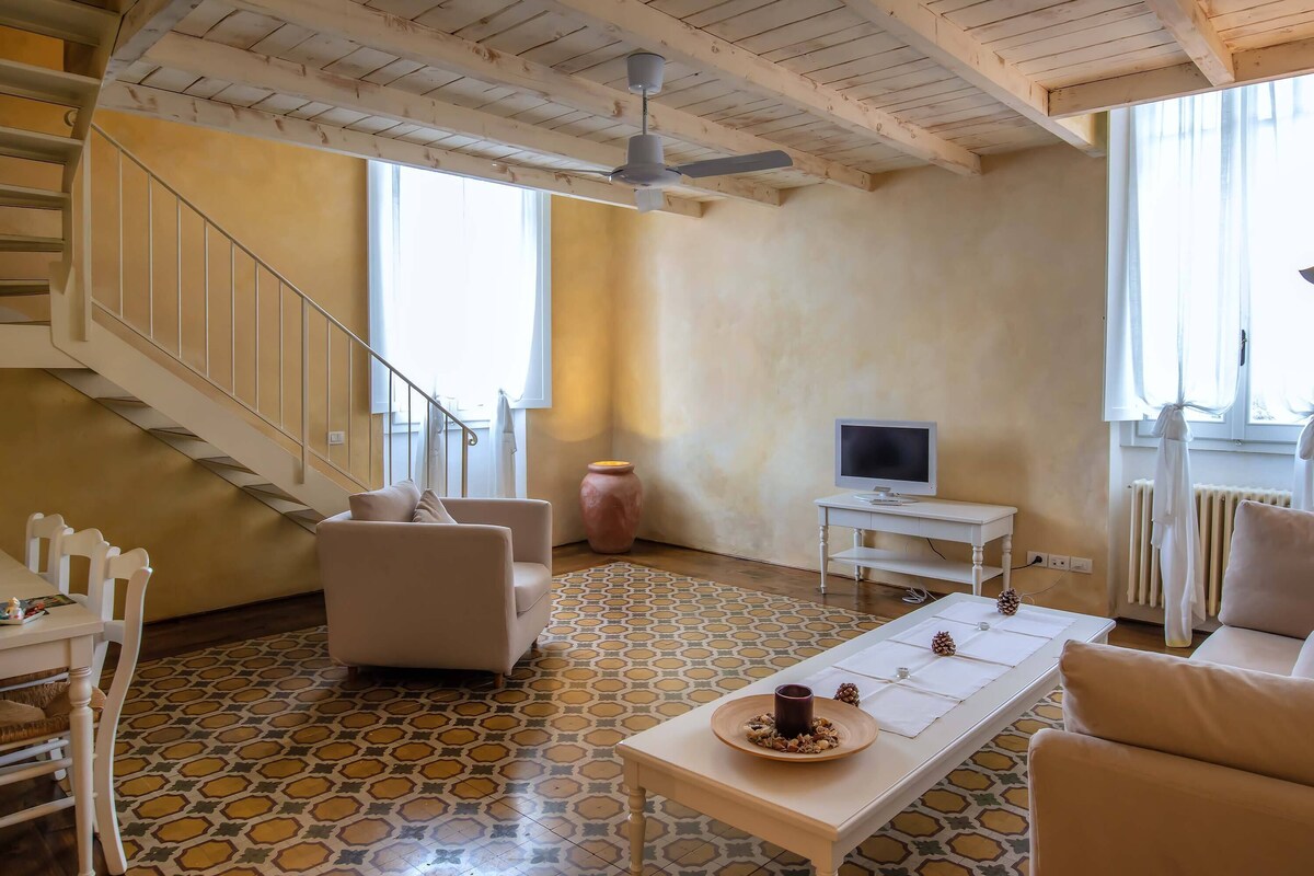 A living room with a patterned floor, a sofa, a coffee table, a TV, and a staircase.