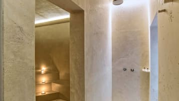 A modern bathroom with a shower, a small seating area with candles, and a ceiling light fixture.