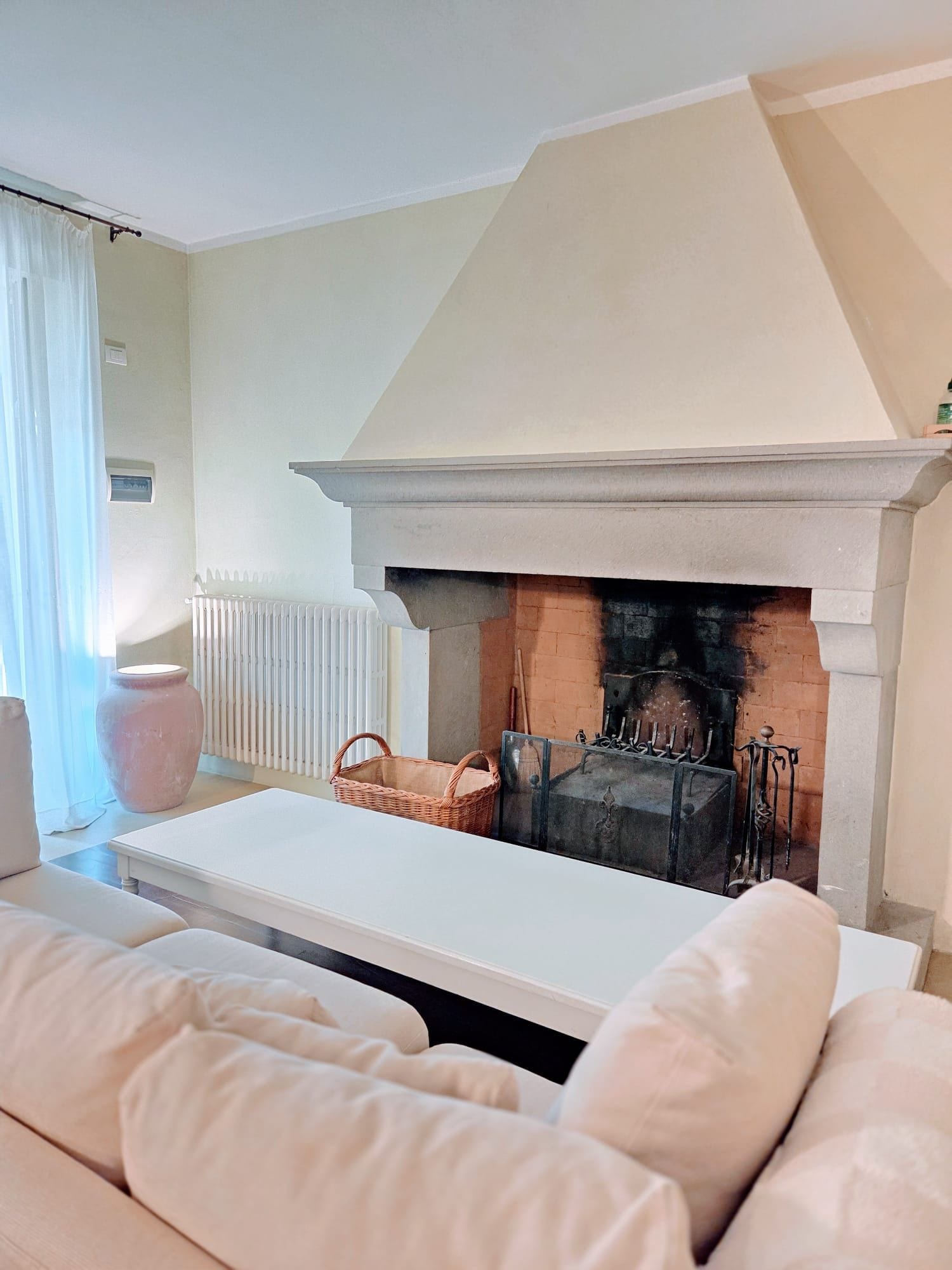Ein Wohnzimmer mit Kamin, einem weißen Sofa, einem Tisch und einer Heizung.