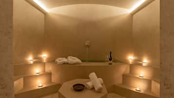 Relax in a serene spa room with a seating area, bathtub, and candles.