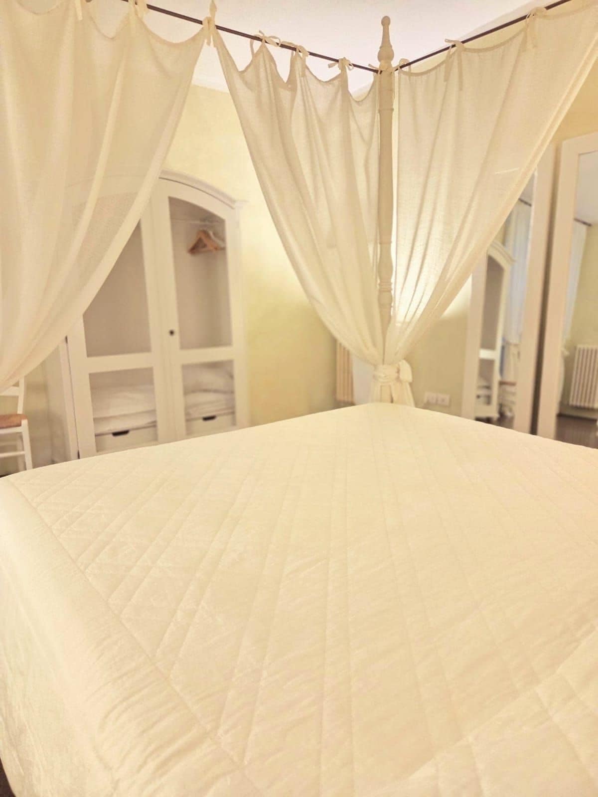 A bed with a canopy and a white wall.