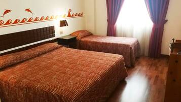 A hotel room with two beds, a nightstand, a lamp, and a window with purple curtains.