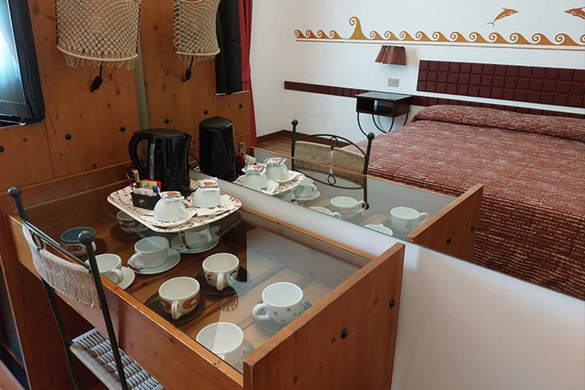Une petite chambre comprenant un lit, une petite table avec un service à thé et un miroir qui reflète le lit.