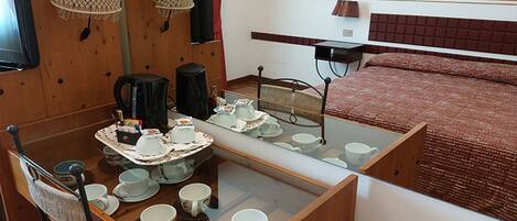 Une petite chambre comprenant un lit, une petite table avec un service à thé et un miroir qui reflète le lit.