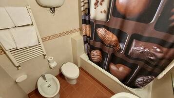 A bathroom with a toilet, bidet, and sink. There is a towel rack with towels and a toilet paper holder.
