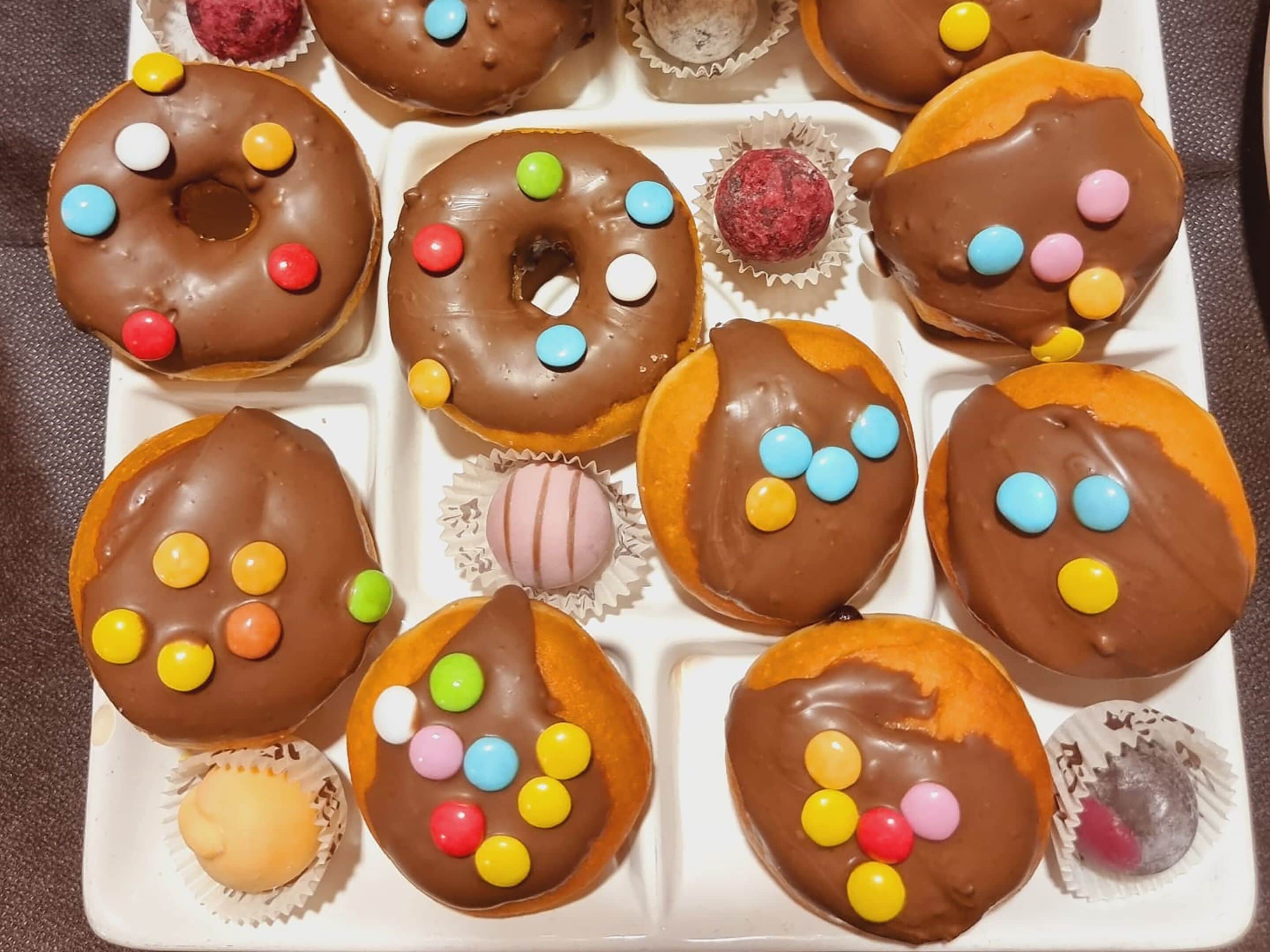 Un plateau rempli de diverses pâtisseries enrobées de chocolat, accompagnées de bonbons colorés.
