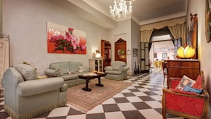 A living room with a checkered floor, green sofas, a wooden coffee table, and a chandelier. - Hotel Residenza In Farnese (Rome)