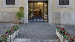 A hotel entrance with a checkered entrance mat, a chandelier, and a sign reading "HOTEL R". - Hotel Residenza In Farnese (Rome)