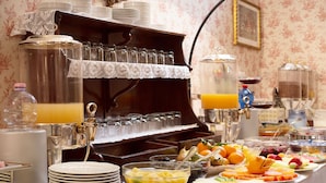 A buffet setup with various food items and beverages, including fruits, a fruit salad, and a juice dispenser. - Hotel Residenza In Farnese (Rome)
