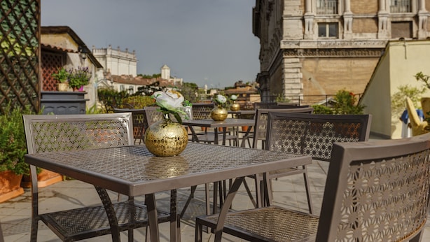 An outdoor seating area with metal tables and chairs, a decorative vase, and potted plants. - Hotel Residenza In Farnese (Rome)