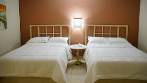A room with two beds, a small round table, and a wall-mounted light fixture. - Hotel Posada del Sol Inn (Torreón)