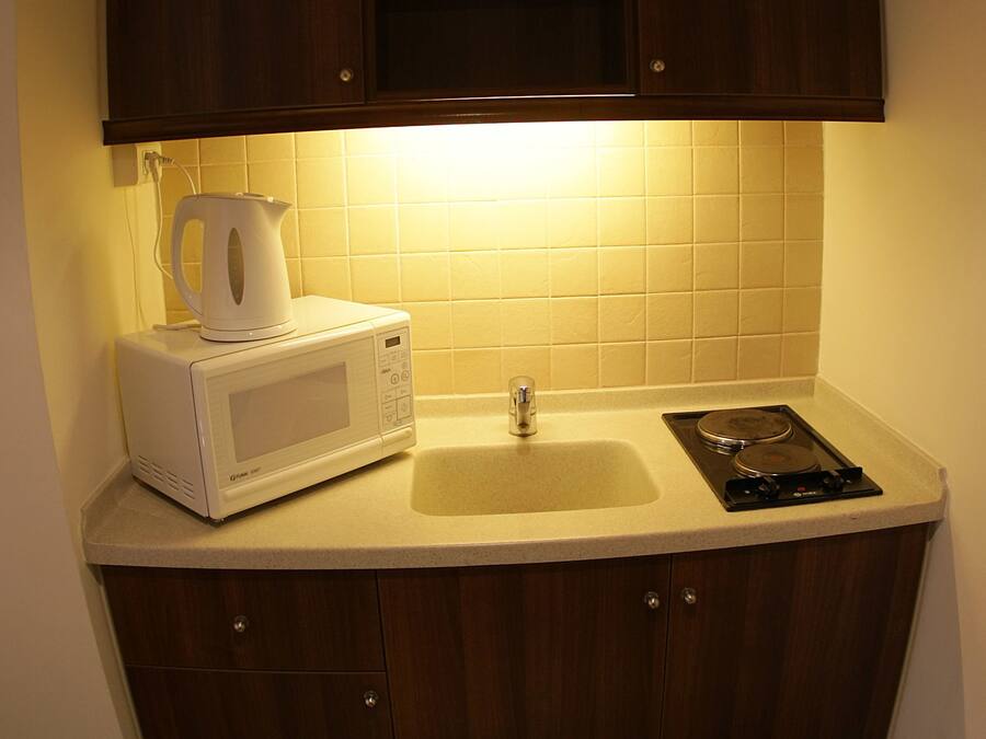 Una cocina pequeña con microondas, hervidor y estufa.