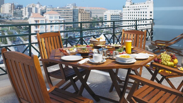 A balcony with a table set for breakfast, overlooking a cityscape. - Markazia Suites (Beirut)