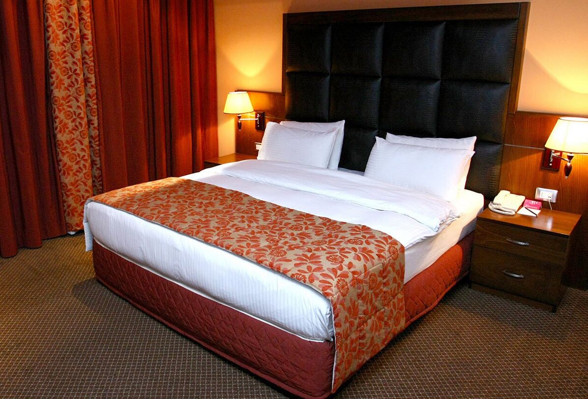 Ein Hotelzimmer mit einem großen Bett, zwei Nachttischen und einer Kopfteil.