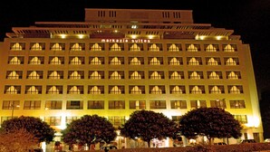 A multi-story hotel with a row of uniformly lit windows and a sign reading "markazia suites". - Markazia Suites (Beirut)