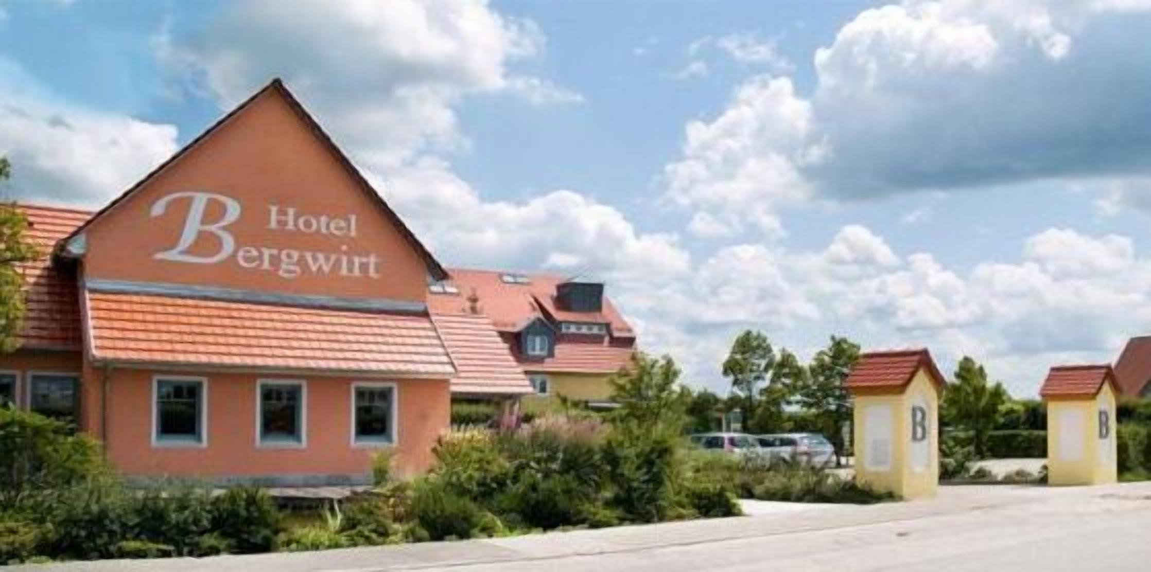 A hotel named 'Hotel Bergwert' with a prominent 'B' logo, surrounded by greenery and other similar buildings.