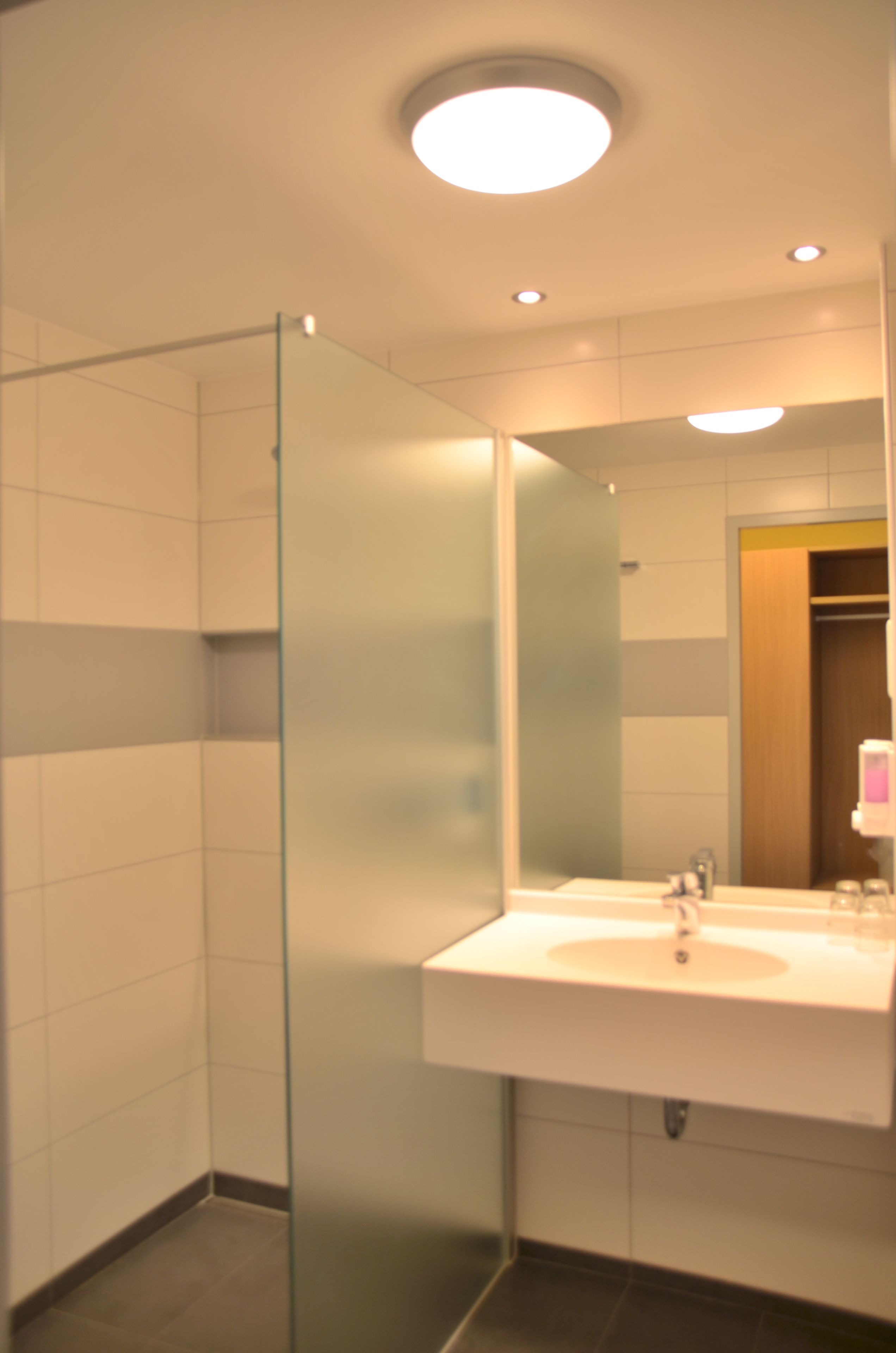 Un baño moderno con cabina de ducha de vidrio, un lavabo blanco y un espejo.