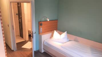 A hotel room with a bed, a nightstand, a mirror, and a shower area.