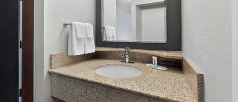 Une salle de bain avec un comptoir en granit, un lavabo et un miroir.
