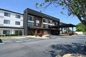 Un hotel Courtyard by Marriott con diseño moderno, entrada cubierta y estacionamiento con espacios para discapacitados.
