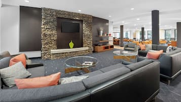 Un área de estar moderna con una pared de acento de piedra, un televisor de pantalla plana y una disposición de asientos que incluye sofás y sillones.
