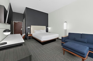 Una habitación de hotel con cama, escritorio, silla, sofá y televisor.