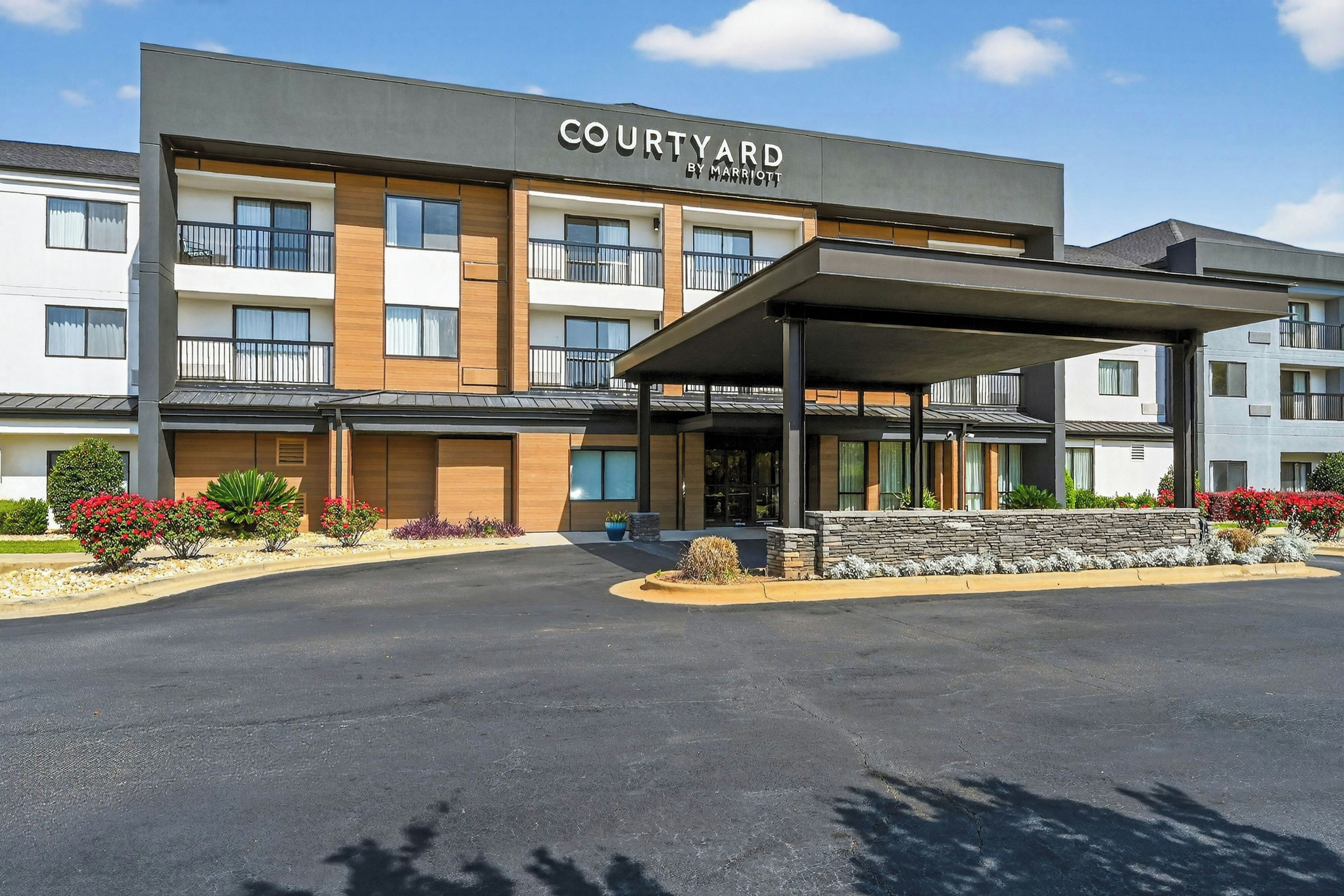 A Courtyard by Marriott hotel with a covered entrance and a landscaped front yard.