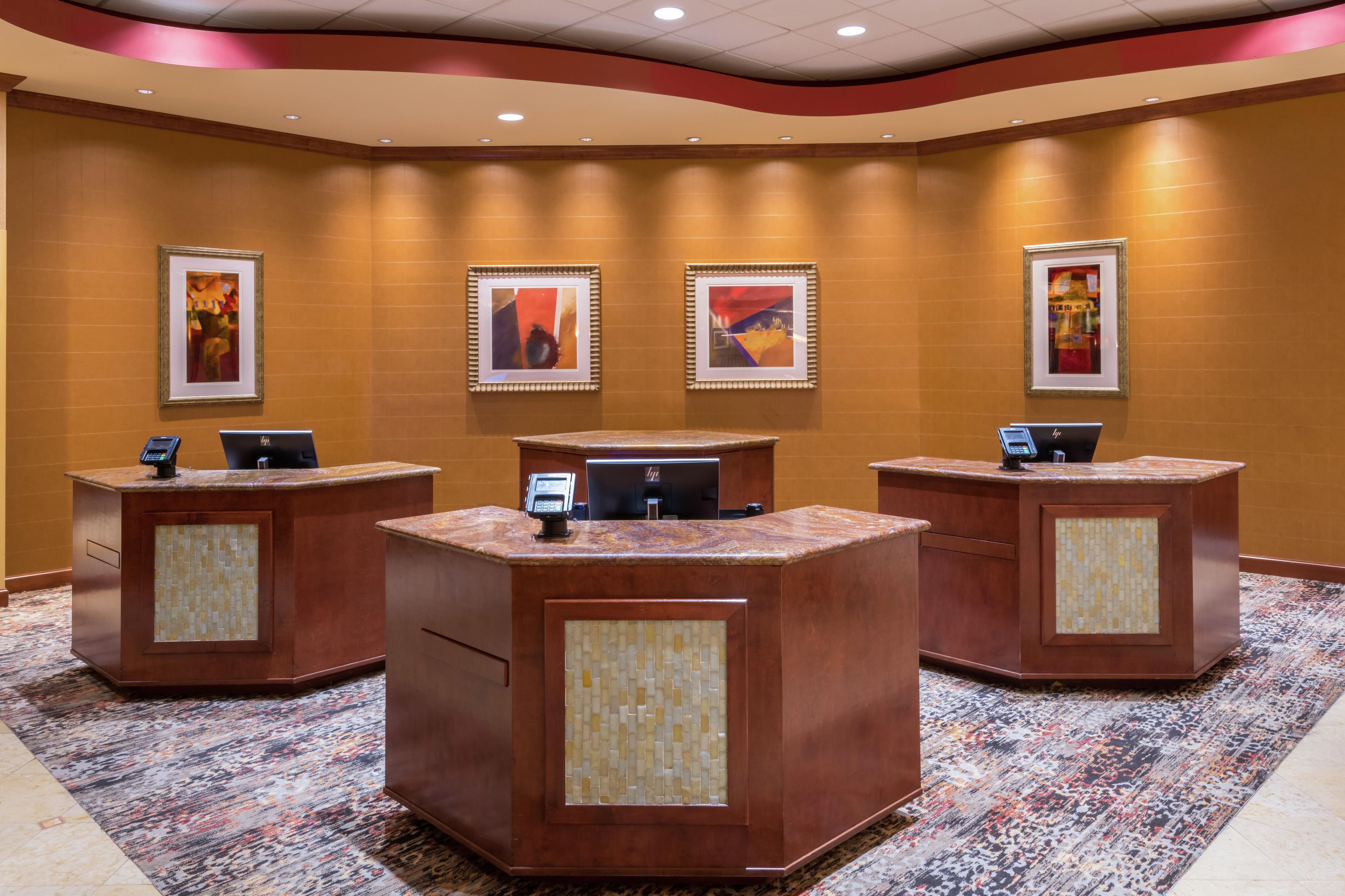 A reception area with three counters, each equipped with a computer and a phone. The walls are adorned with framed artwork.