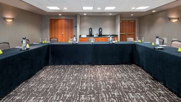 Ein Konferenzraum mit langem Tisch, Stühlen, einer Kaffeestation und einer kleinen Küche.