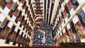 A high-rise hotel with multiple floors, each featuring balconies with red railings and green plants. The interior includes a central atrium with a winding pathway and seating areas. - Embassy Suites by Hilton St. Louis St. Charles (St. Charles)