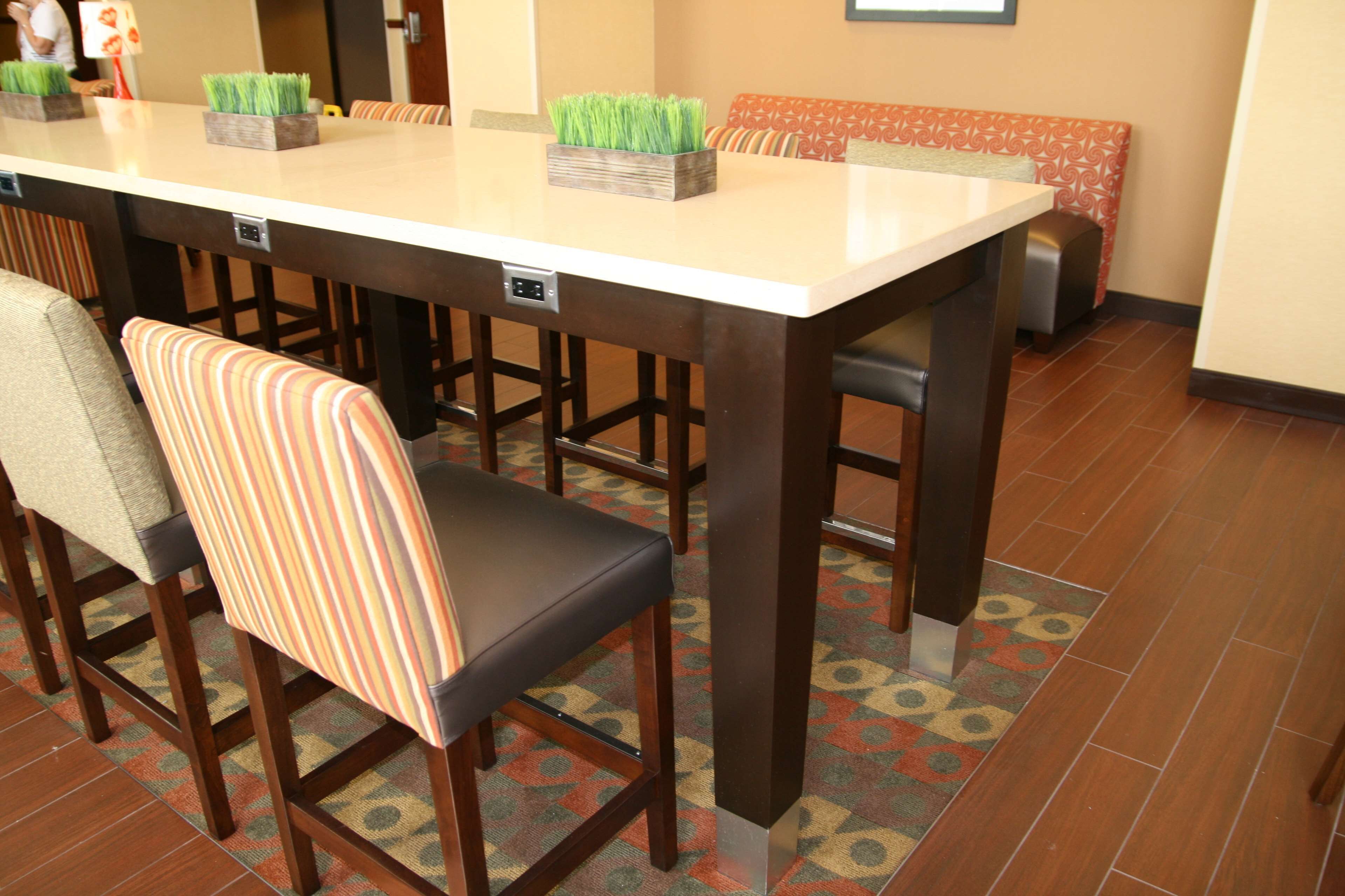 Un espace repas avec une longue table, des tabourets de bar et des carreaux de sol à motifs.