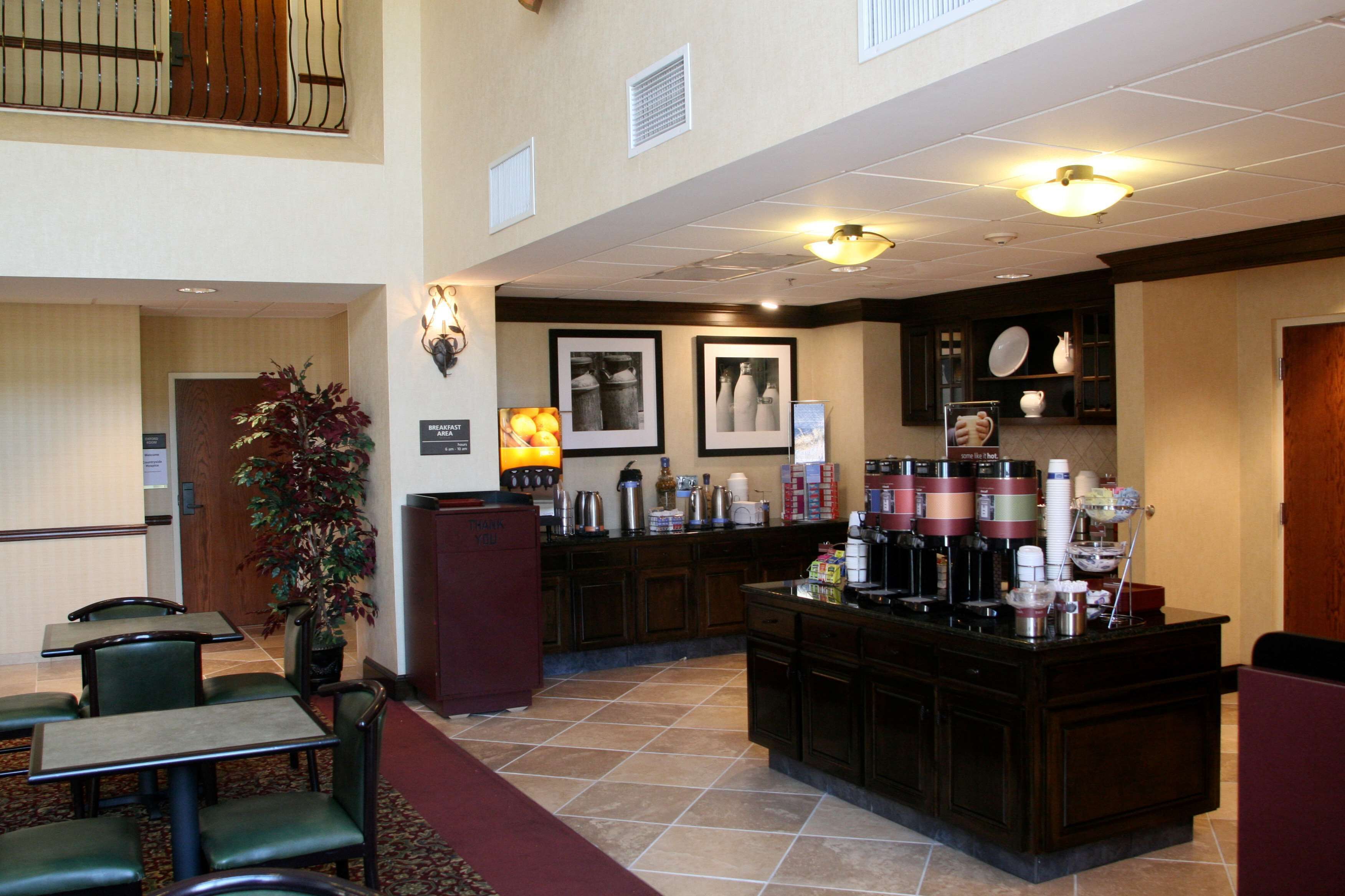 Un vestíbulo de hotel con mostrador de recepción, zona de estar y kitchenette.