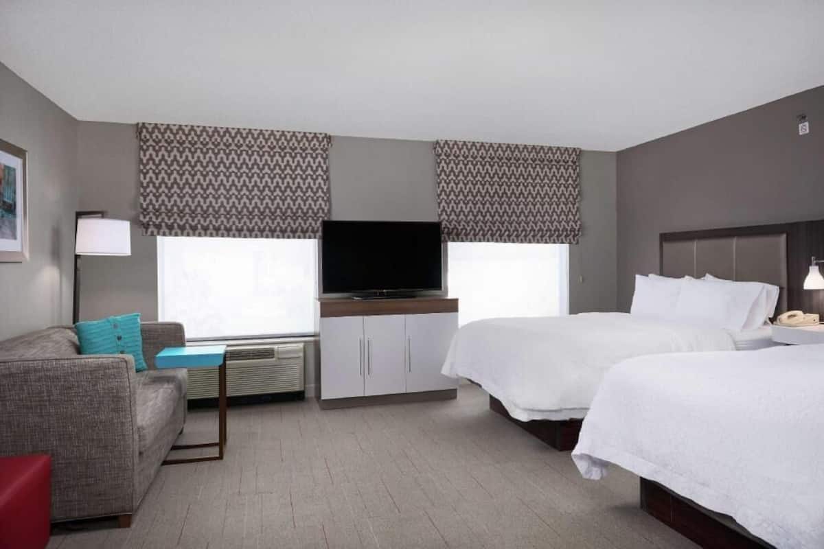 Habitación de hotel con dos camas, un sofá, un televisor y un escritorio.