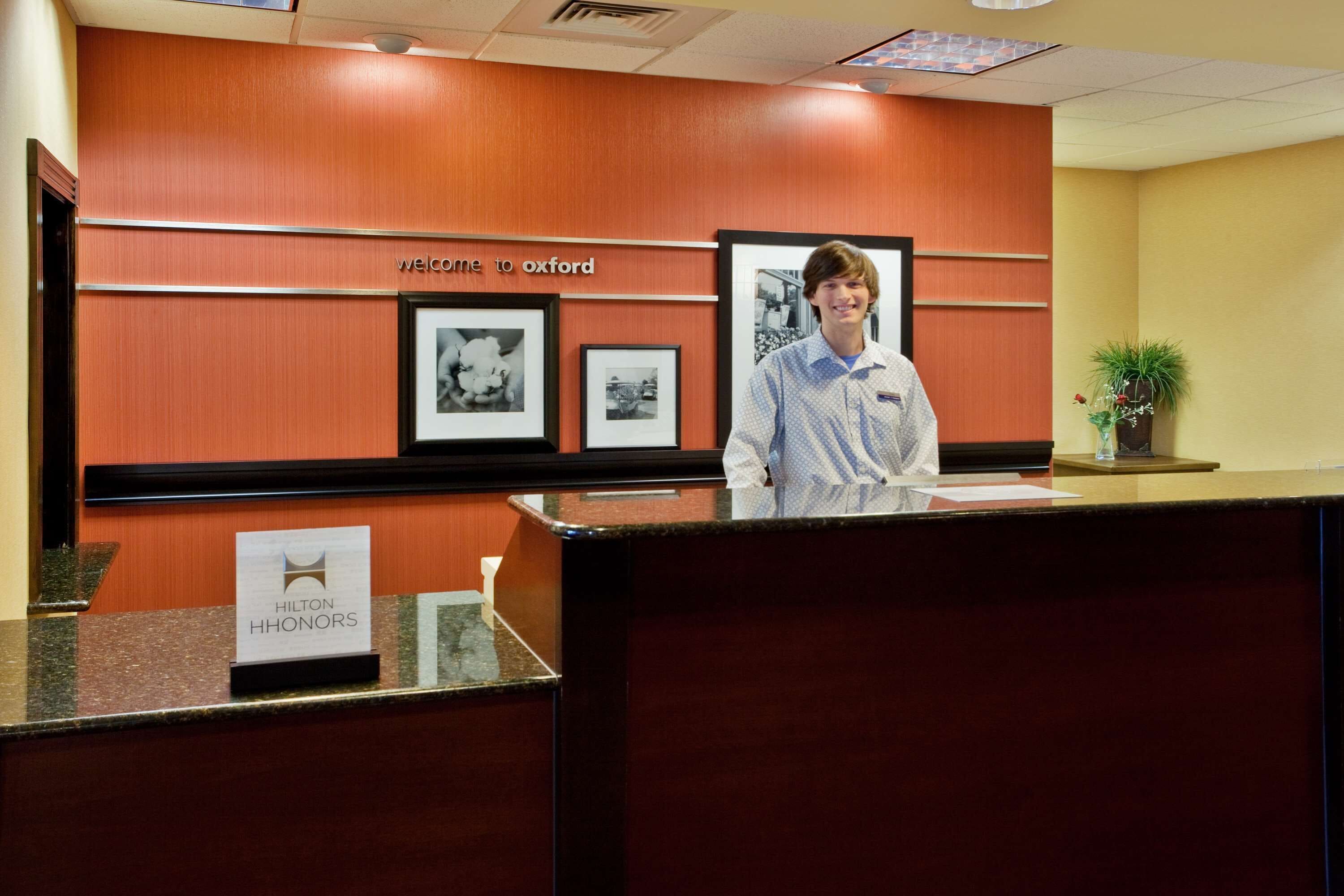 Een receptiebalie met een bord waarop ‘Hilton Honors’ staat en een welkomstbord erboven.