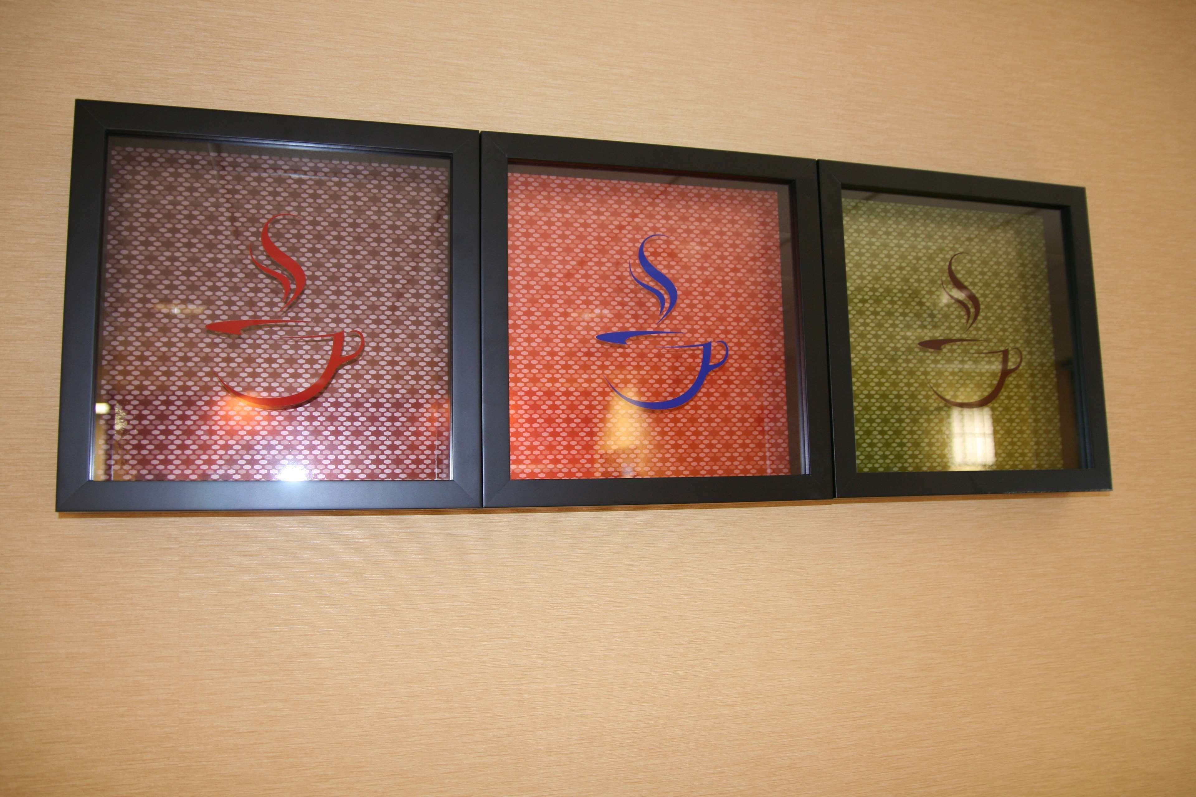 Three framed glass panels with abstract designs on a wall.