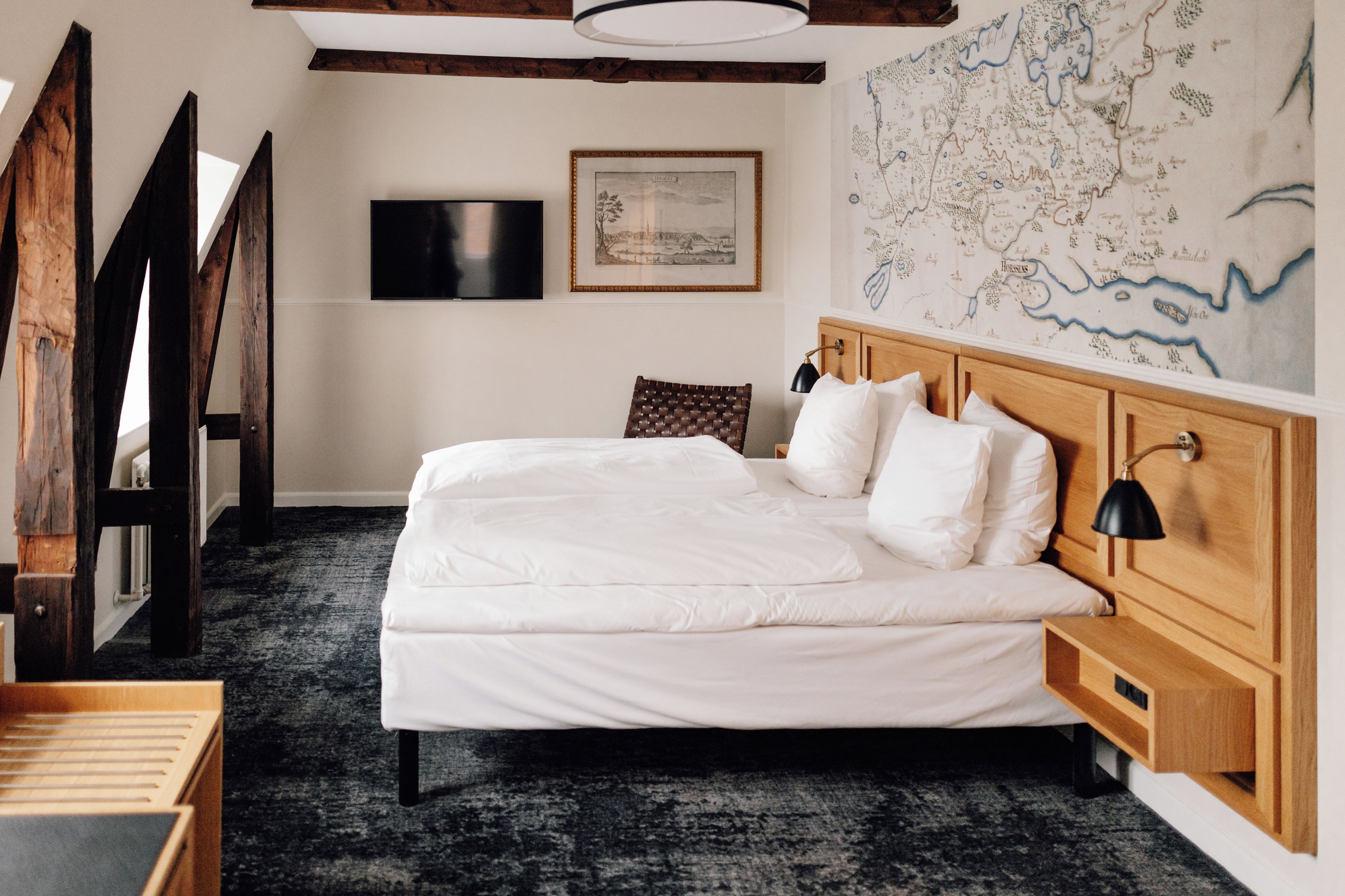 Un dormitorio con una cama grande, cabecera de madera, un mapa en la pared y un televisor de pantalla plana.