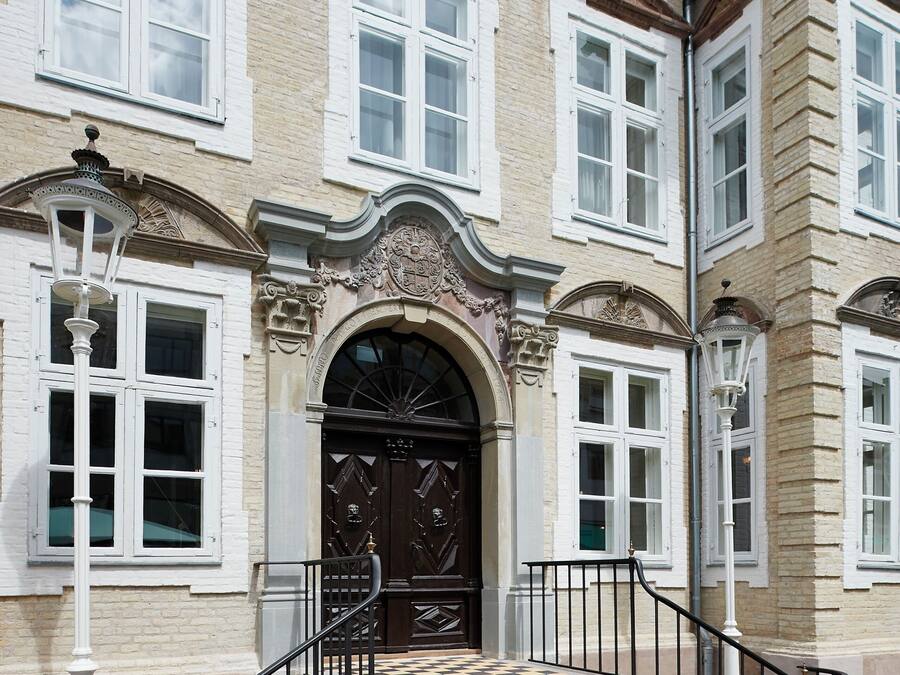 Un edificio storico con un ingresso imponente, dettagli architettonici elaborati e una scalinata che conduce all'ingresso.