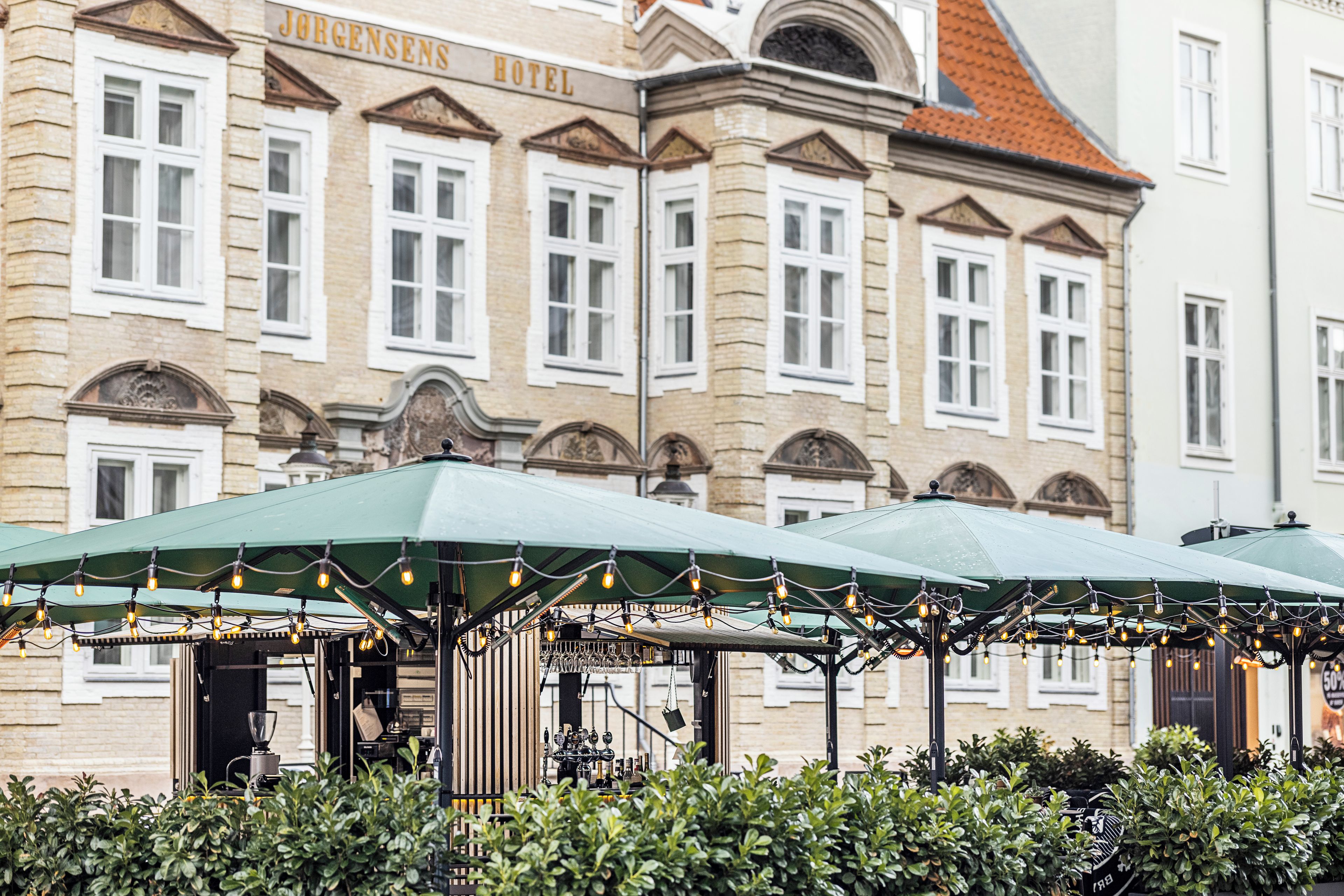 A historic building with a sign reading 'Jorgensen's Hotel' and a covered outdoor seating area with string lights.