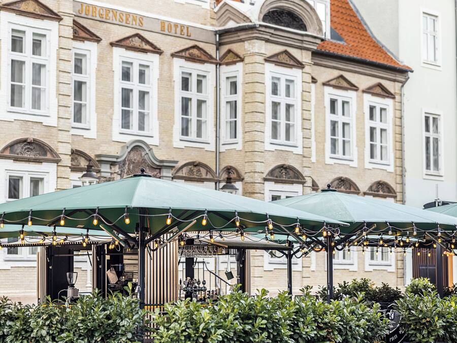 A historic building with a sign reading 'Jorgensen's Hotel' and a covered outdoor seating area with string lights.