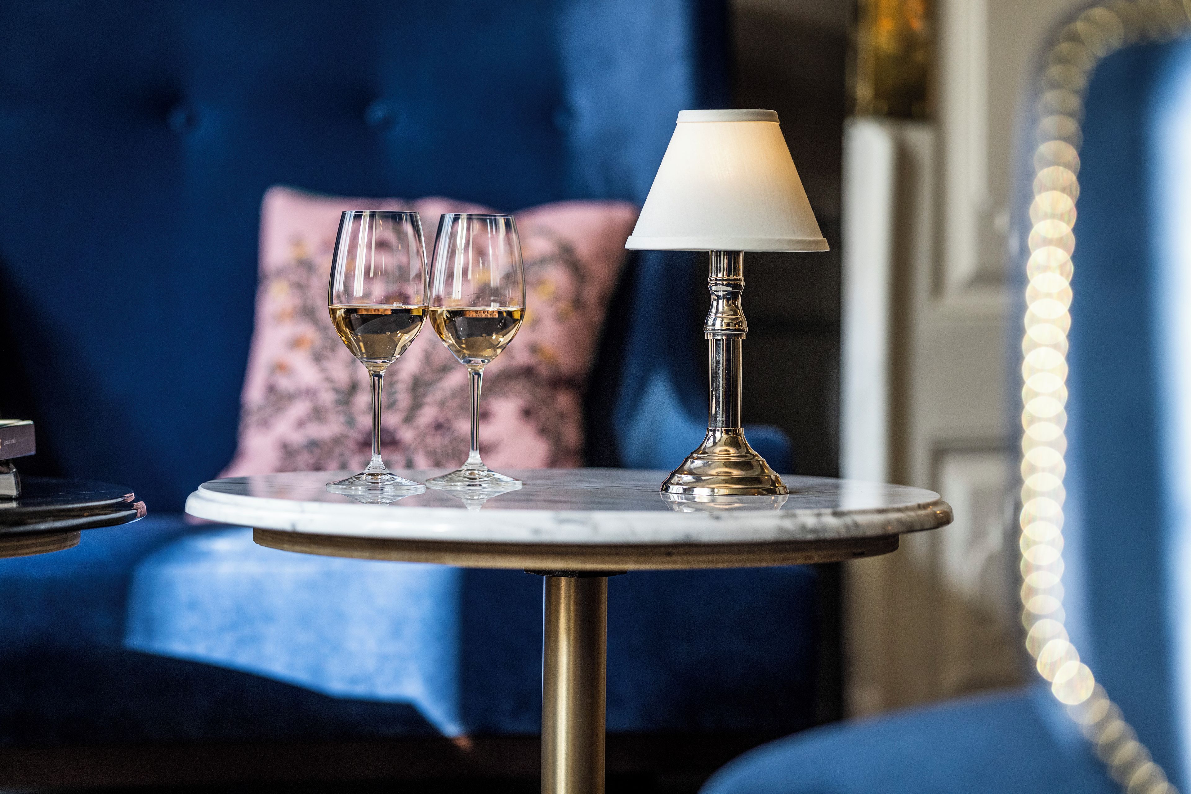 A round table with two wine glasses and a lamp.