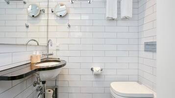 Un baño moderno con lavamanos, dos espejos, inodoro y toallero.