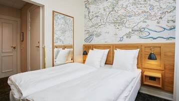 Habitación de hotel con una cama grande, dos mesitas de noche con lámparas, un cabecero de madera y un mapa en la pared.