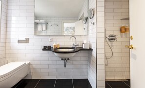 A bathroom with a white sink, black countertop, and a white toilet. There is a mirror above the sink and a towel rack.