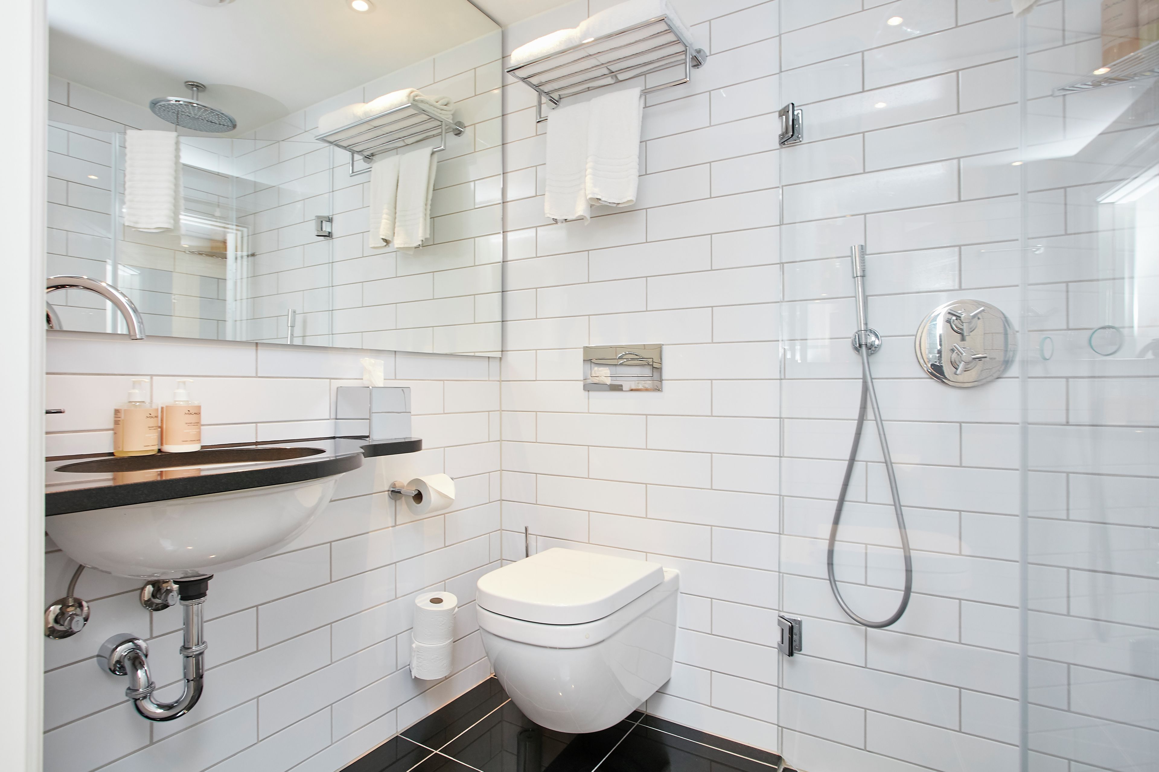Un baño moderno con lavamanos, inodoro y ducha blancos.
