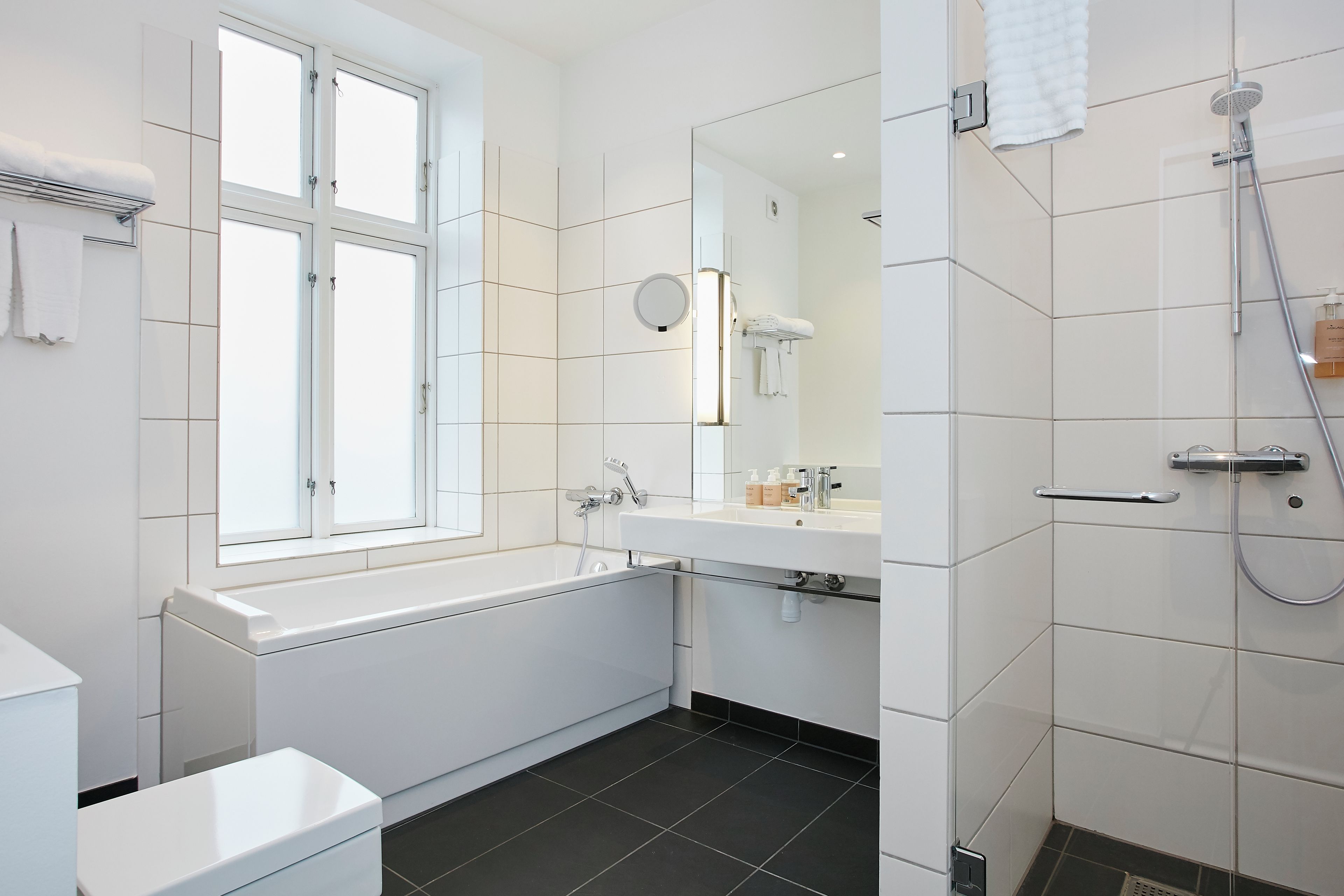A modern bathroom with a bathtub, a sink, a mirror, and a shower.