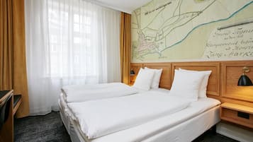 Ein Hotelzimmer mit zwei Betten, einem hölzernen Kopfteil, einer Karte an der Wand und einem Fenster mit transparenten Vorhängen.